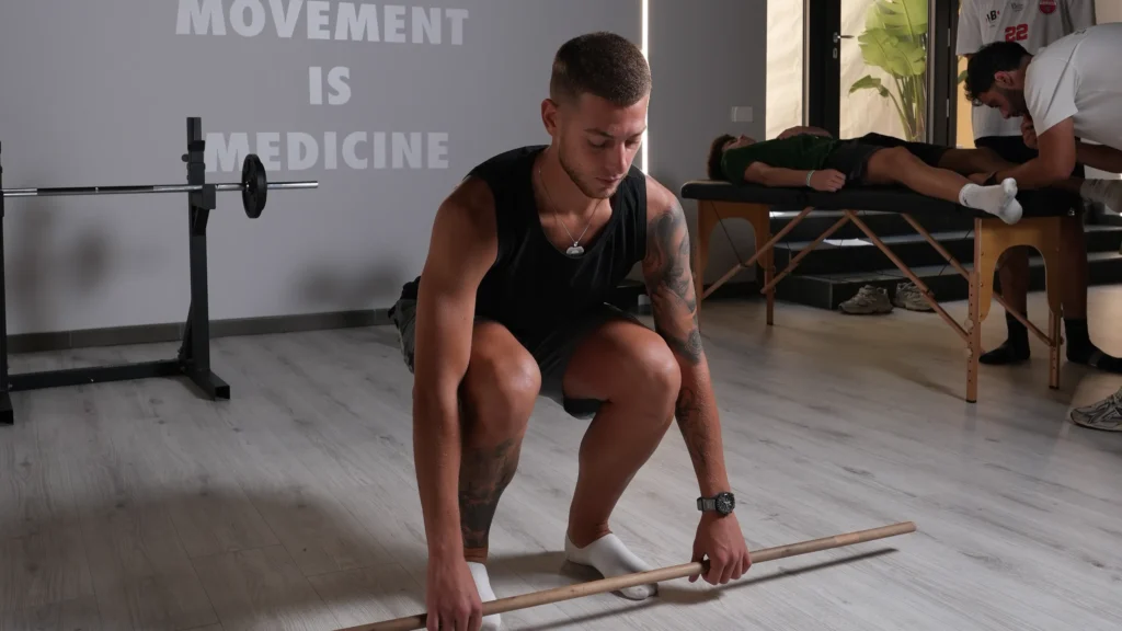 Atleta durante uno squat con bastone nel percorso di ritorno allo sport