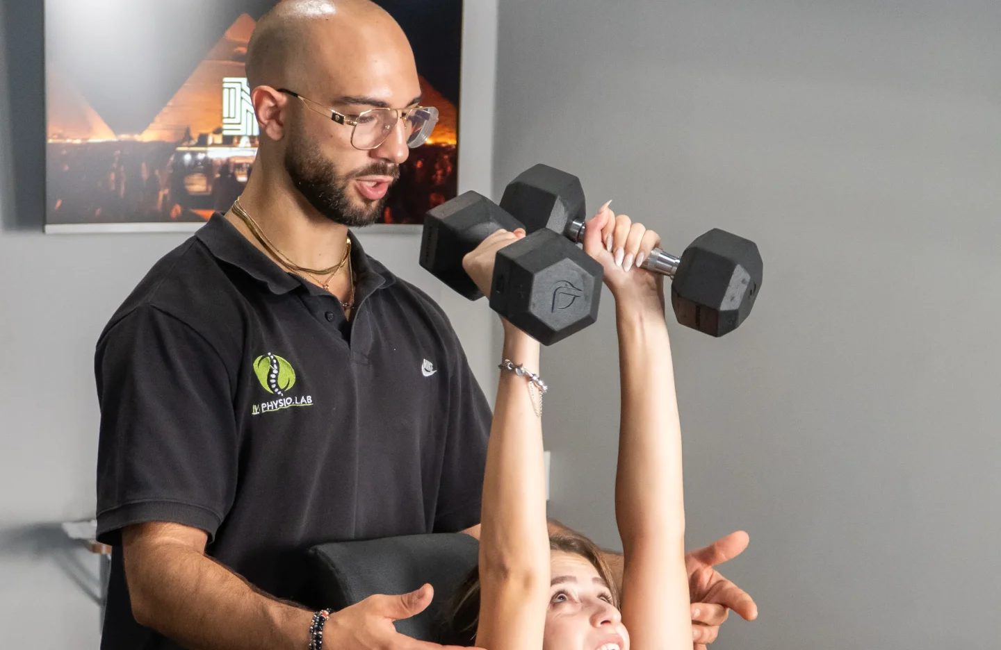 Personal trainer che segue un esercizio con manubri su panca